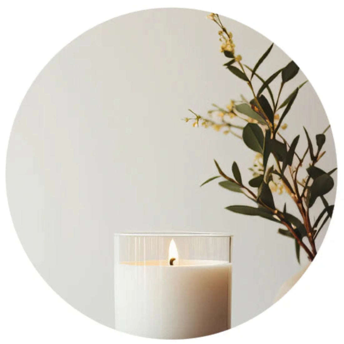 Cream candle alight next to some foliage within a white circle border. 