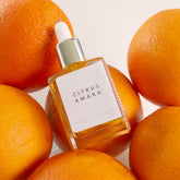 Bottle of citrus Amara scent therapy blend on top of 6 oranges. 