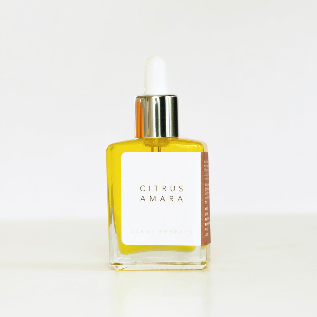 Square glass bottle of citrus Amara scent therapy blend on white surface and white background. 