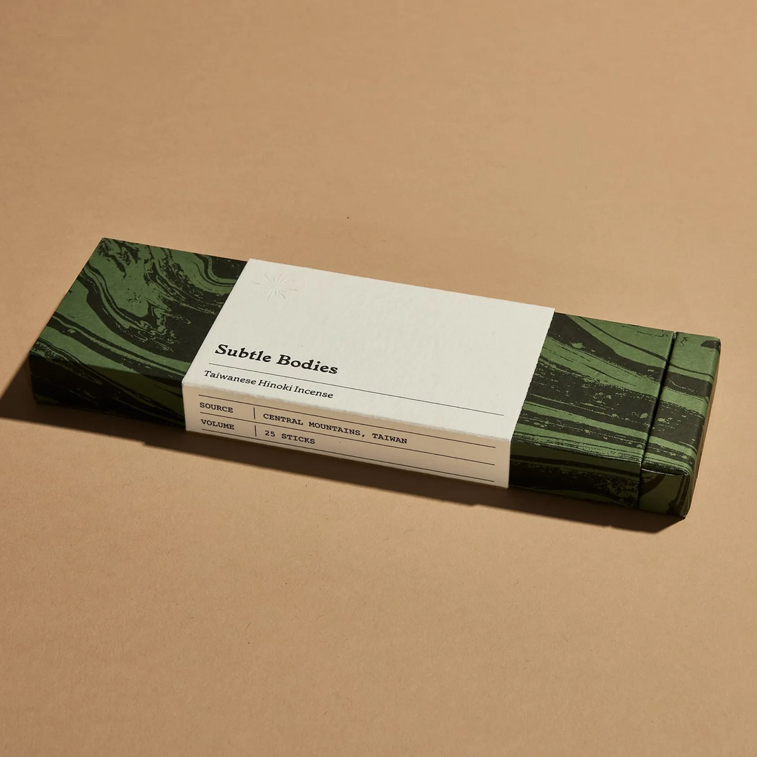 A dark green box of Taiwanese Hinoki incense sticks on beige surface.