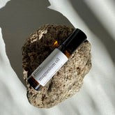 Amber glass roll-on bottle with magnesium oil lying on a stone in soft light. 