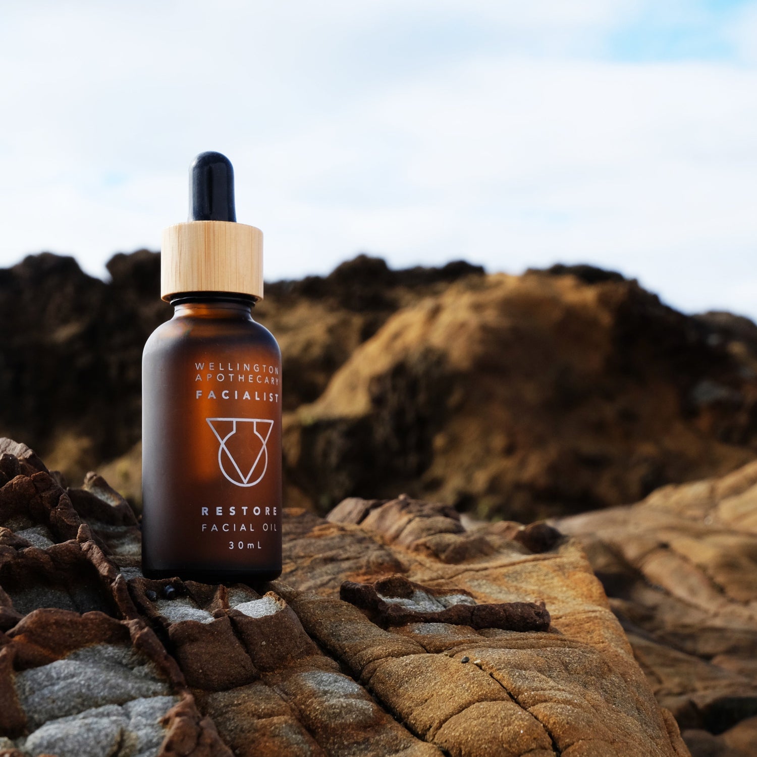 A frosted amber glass bottle of Restore Facial Oil on the south coast rocks of Wellington. 