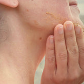 Sandalwood exfoliant powder being applied to jawline. 