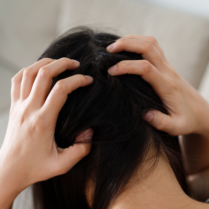 Back view of woman with long black hair massaging her scalp.