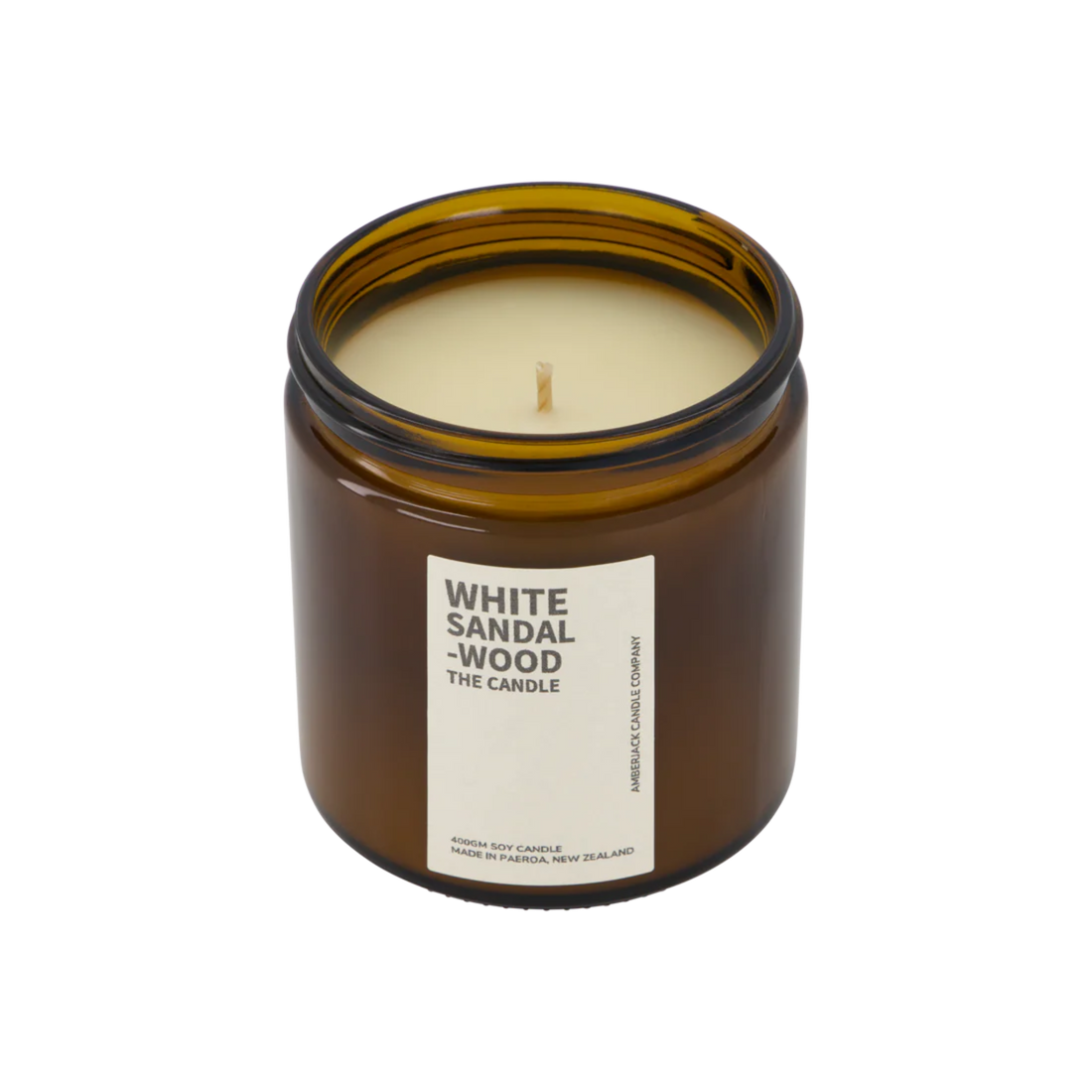 A large amber glass jar containing white sandalwood candle on white background. 