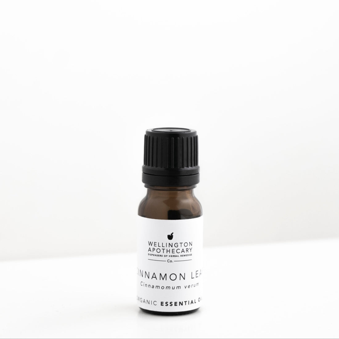 Small amber glass bottle of cinnamon essential oil on white bench. 