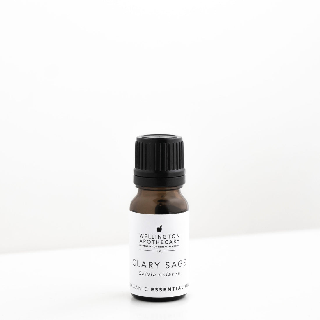 Small amber glass bottle of clary sage essential oil on white bench. 