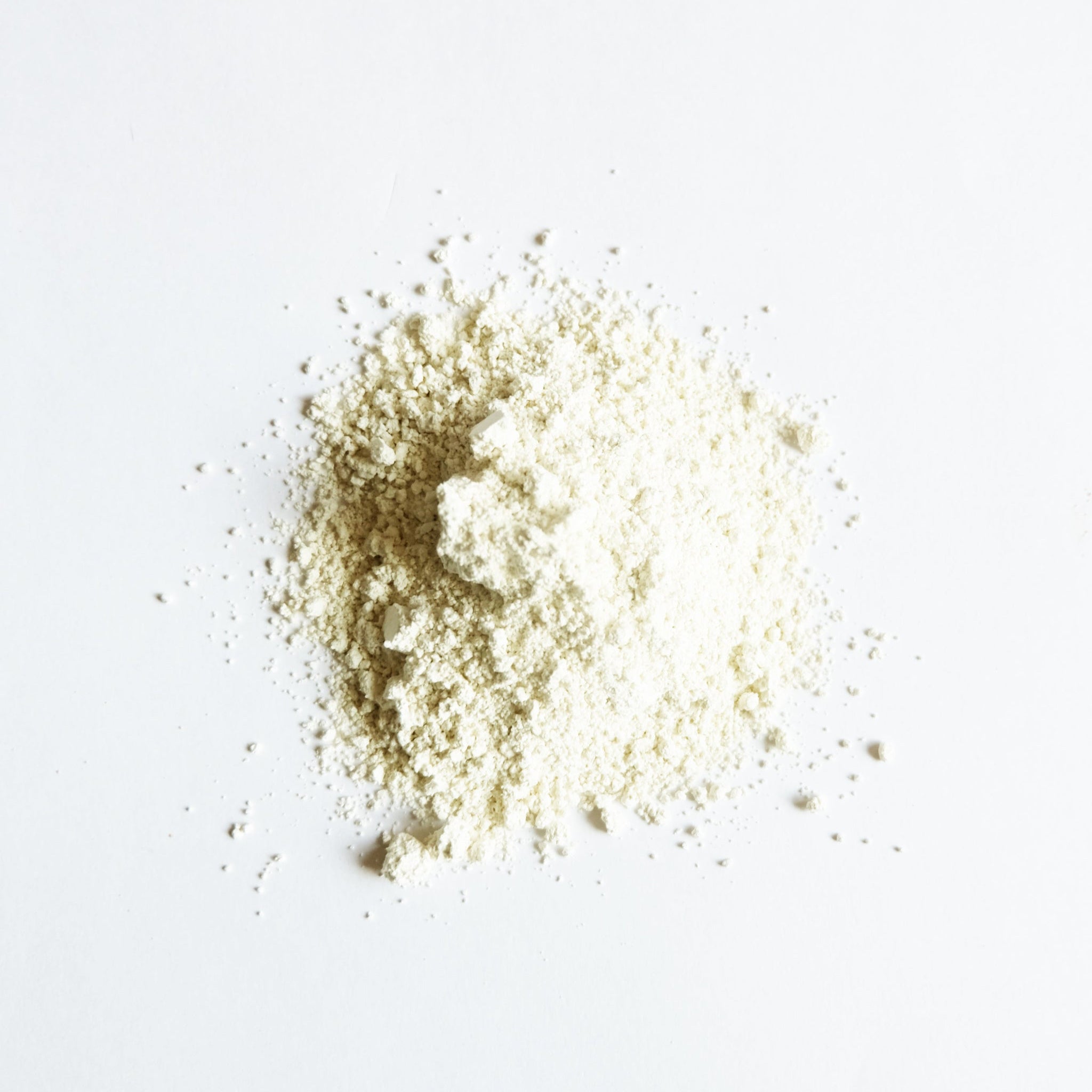 A pile of ivory clay powder on white surface. 