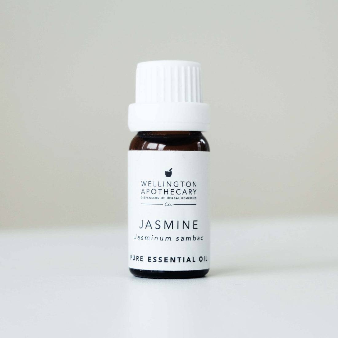 Small bottle of Jasmine essential oil on white bench with soft grey background. 