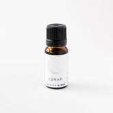 Small amber glass bottle of Lunar essential oil blend on white bench. 