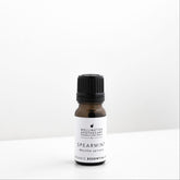 Small amber glass bottle of spearmint essential oil on white bench. 