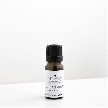 Small amber glass bottle of spearmint essential oil on white bench. 