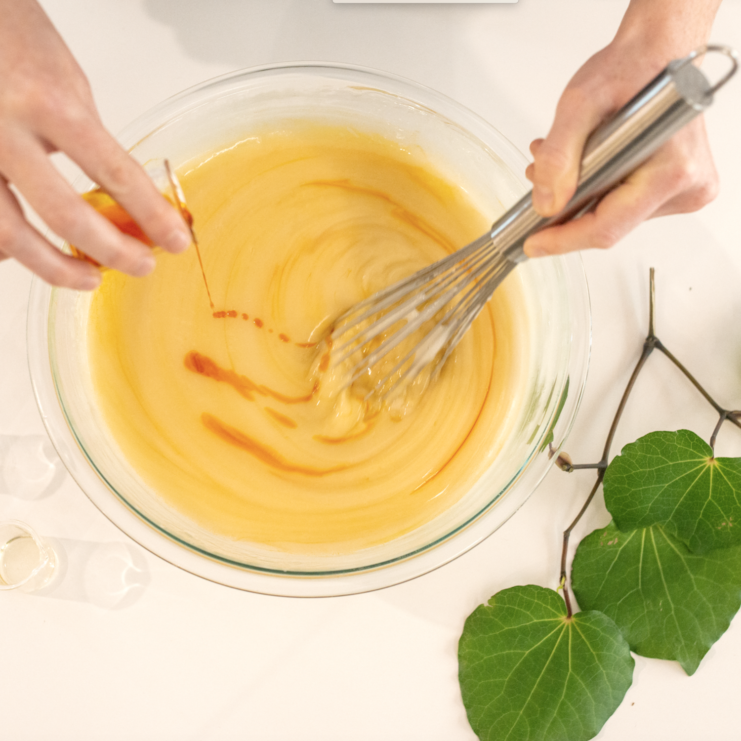 Dark orange sea buckthorn oil being poured into a bowl of yellow serum.