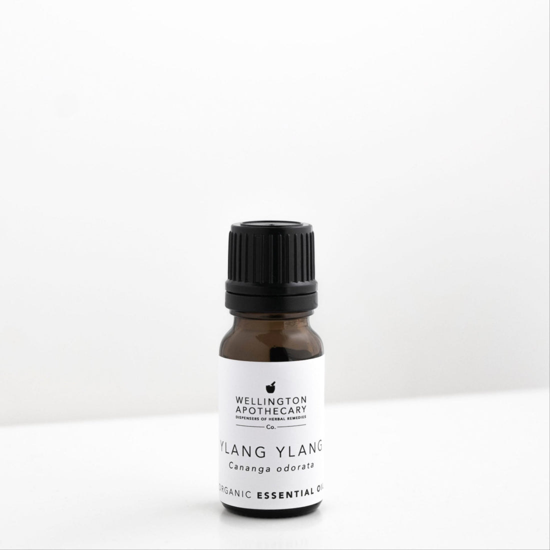 Small amber glass bottle of Ylangylang essential oil on a white bench. 